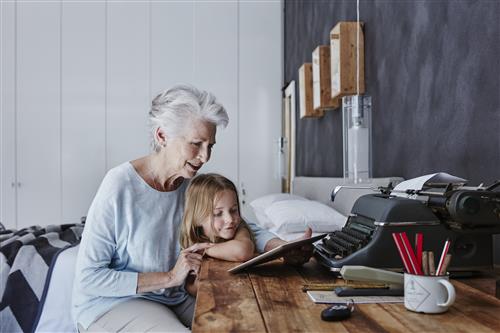 Grandmother and granddaughter looking at tablet at home 