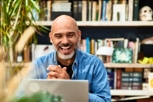A bald man sitting in front of computer smiling