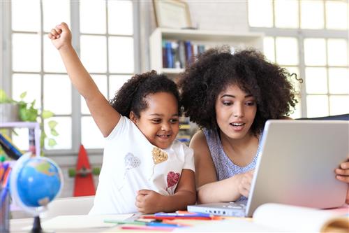 An African American mom and daughter look at a laptop