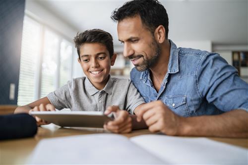 A father and son look at a tablet