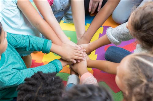 kids are putting their hands in a circle