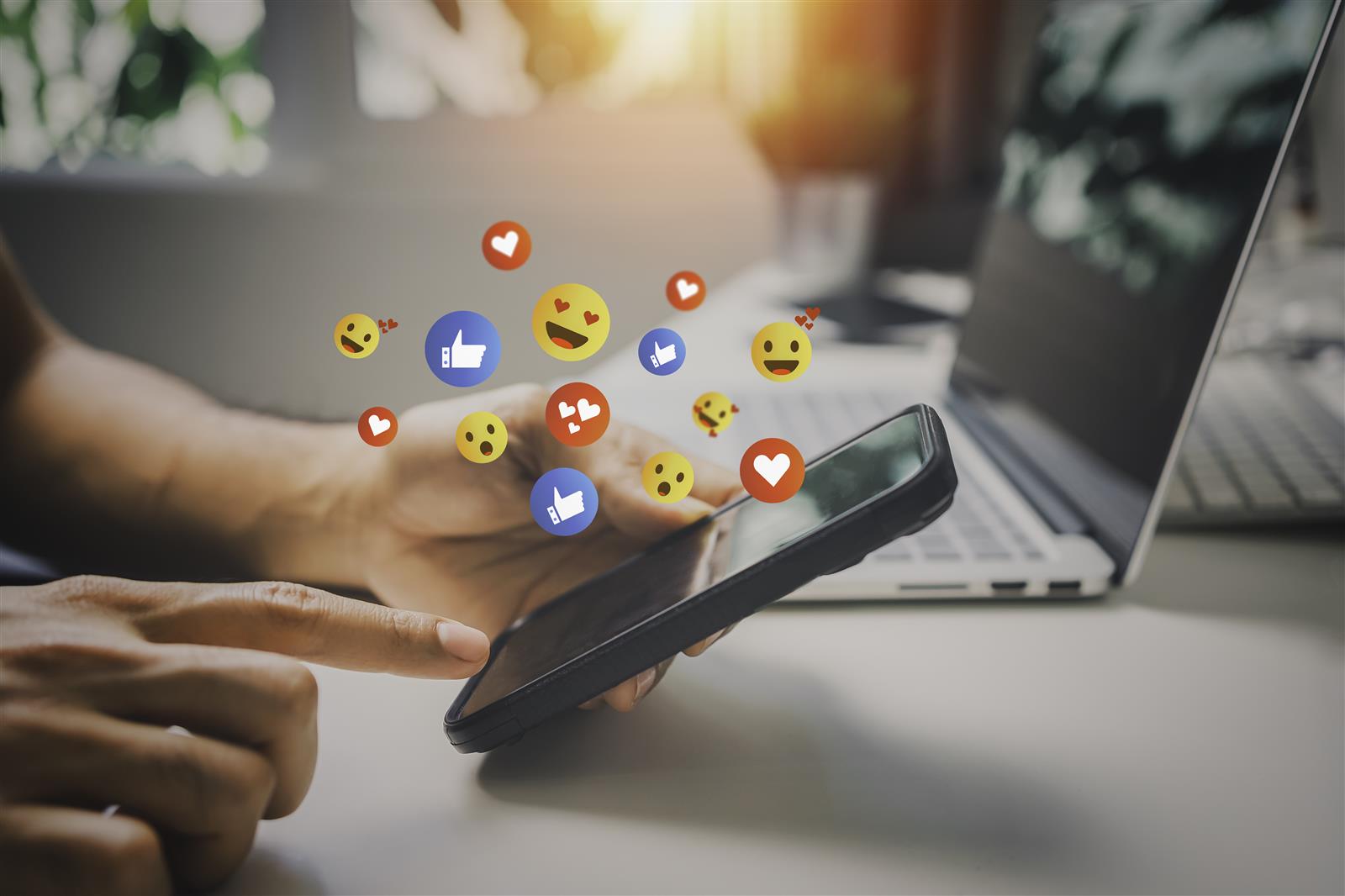  Person typing on phone. A bunch of Facebook reactions are coming from the phone