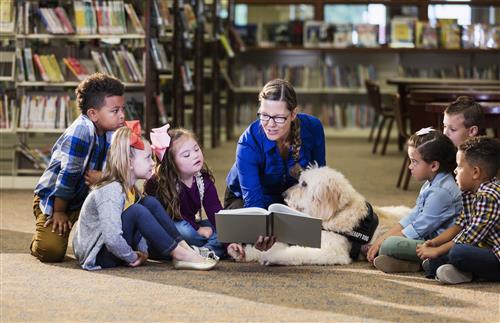 group of kids in a library with teacher