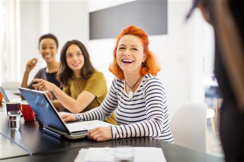 older redheaded woman smiling by computer